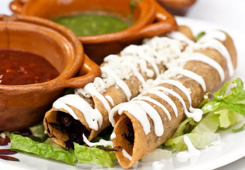 Tacos dorados con crema y queso