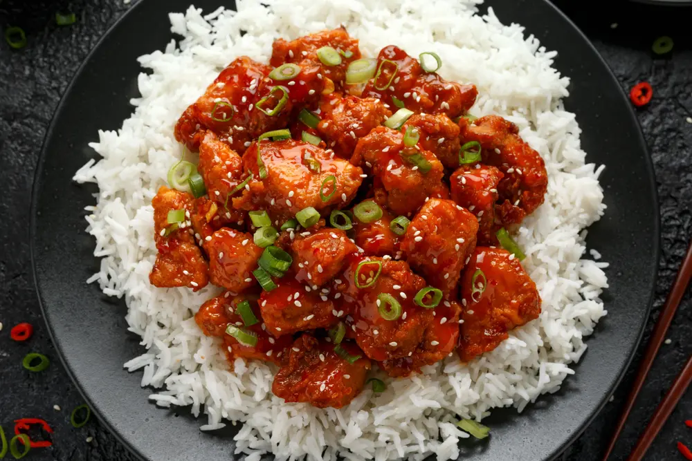 Plato de pollo a la naranja "Pollo General Tso" sobre una cama de arroz