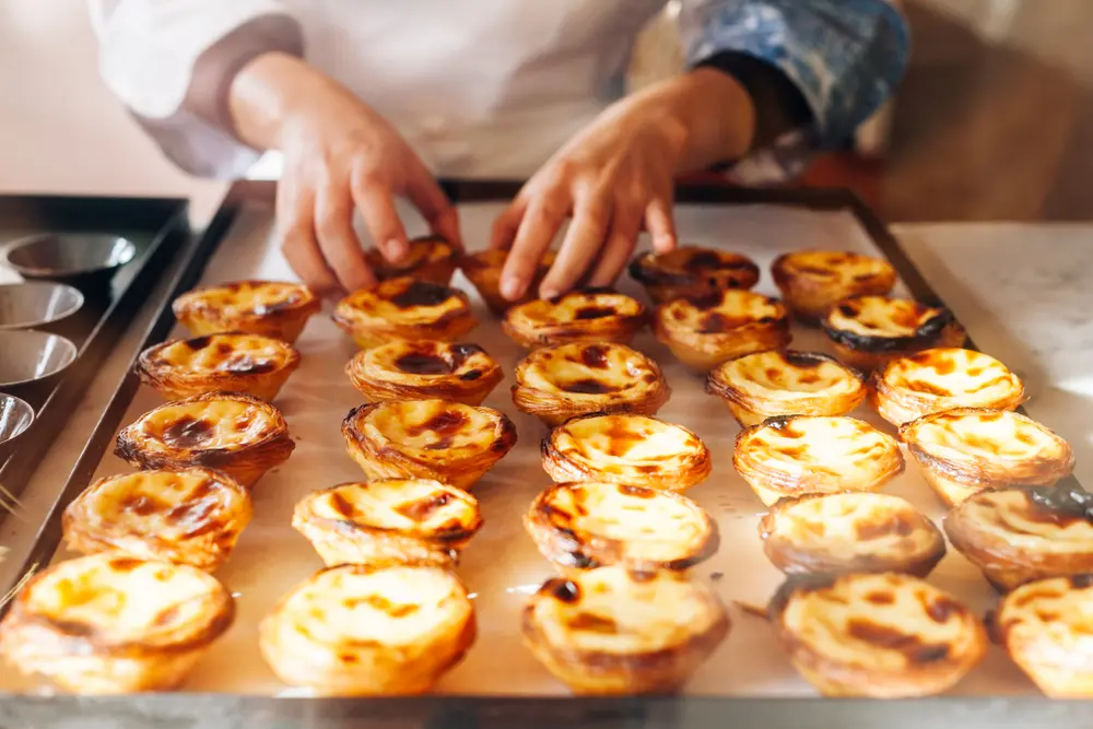 Panadero portugués acomodando Pastel de Belém