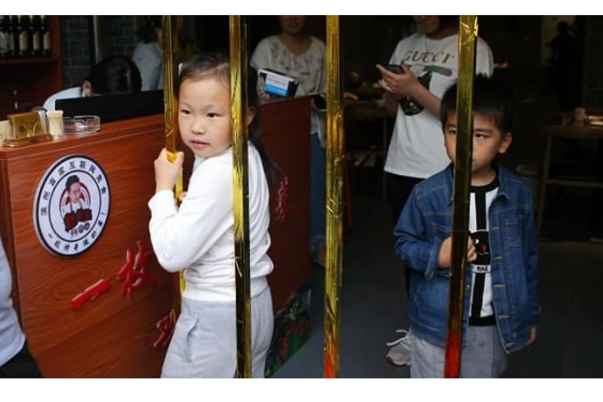 Una niña intenta pasar por la barra más estrecha de un restaurante de la provincia de Shandong.