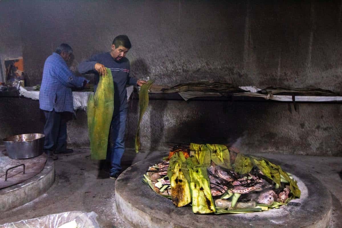Barbacoa de borrego, preparación en horno de tierra con pencas de maguey.