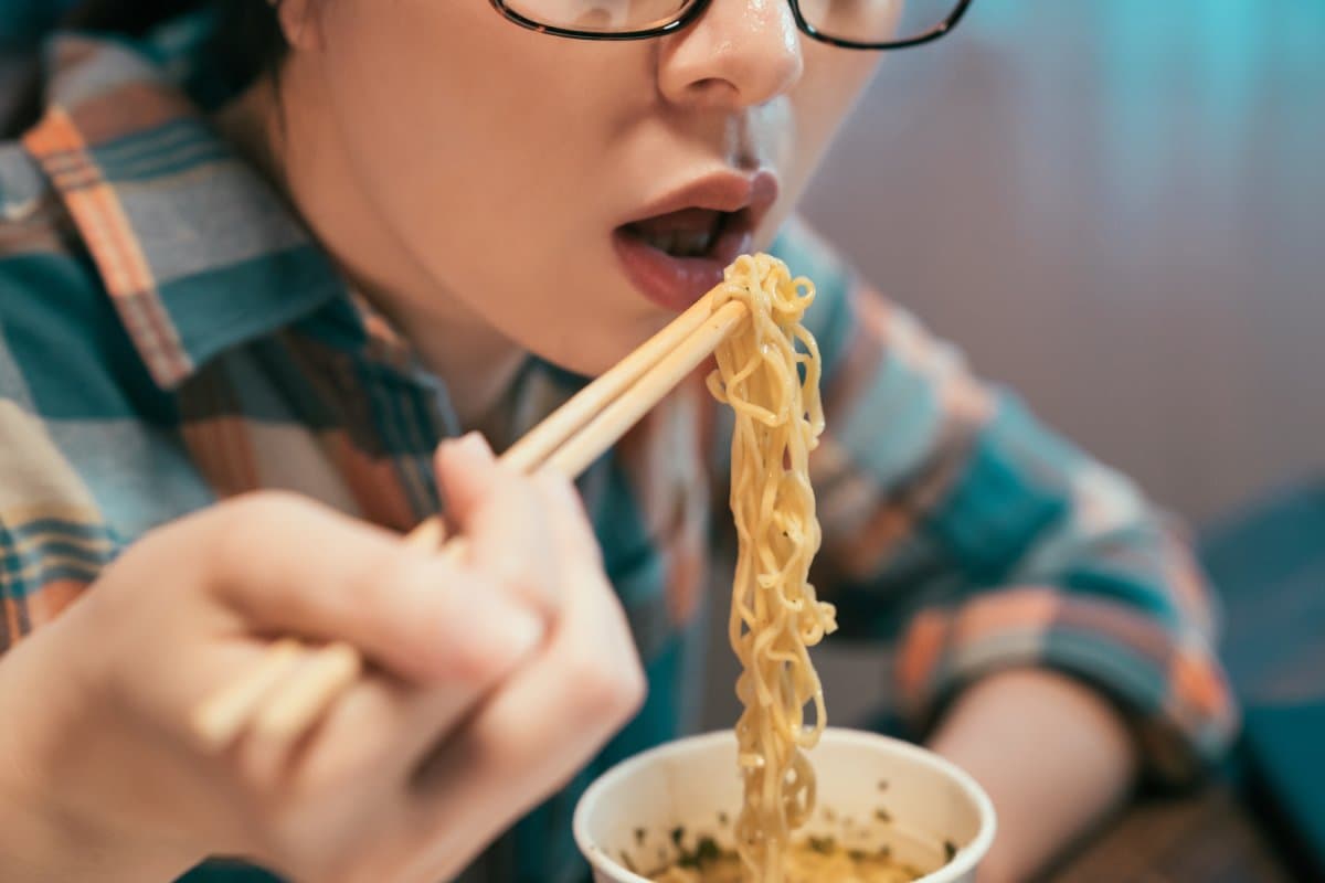 persona comiendo ramen instantáneo con palillos chinos