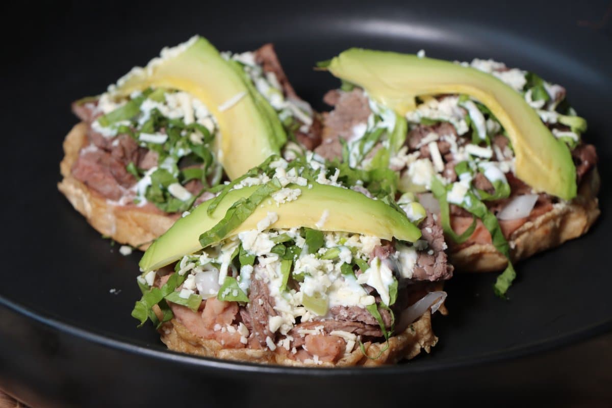 Sopes mexicanos con carne y rebanadas de aguacate.