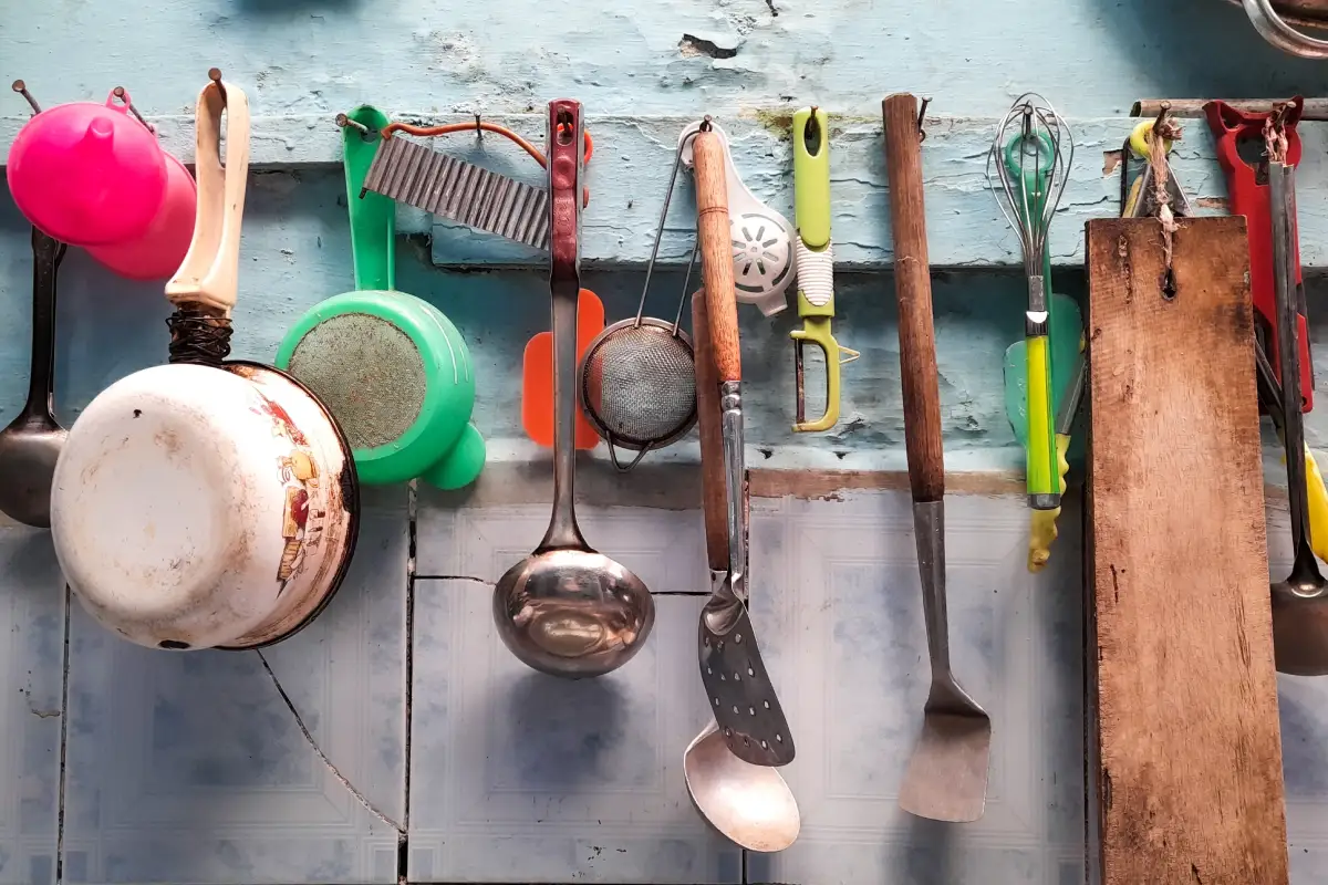 En una pared de una cocina mexicana están colgando cucharas, ollas, coladeras que se usan para cocinar