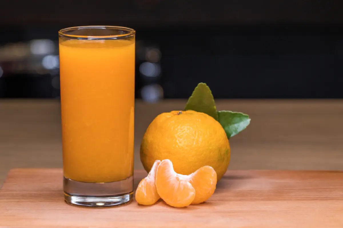 vaso grande de jugo de mandarina y gajos de mandarina
