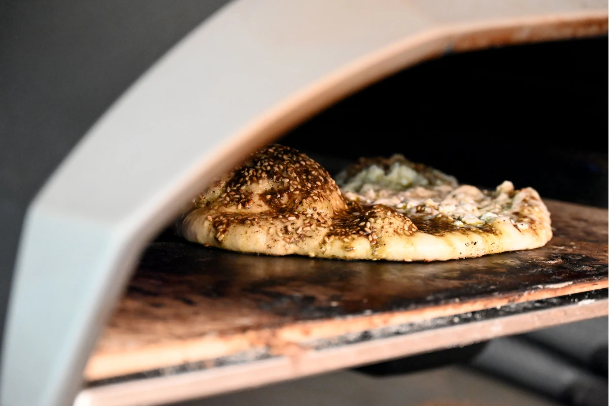 Al interior de un horno de piedra se encuentra cocinando un manushe, un platillo típico de Líbano.