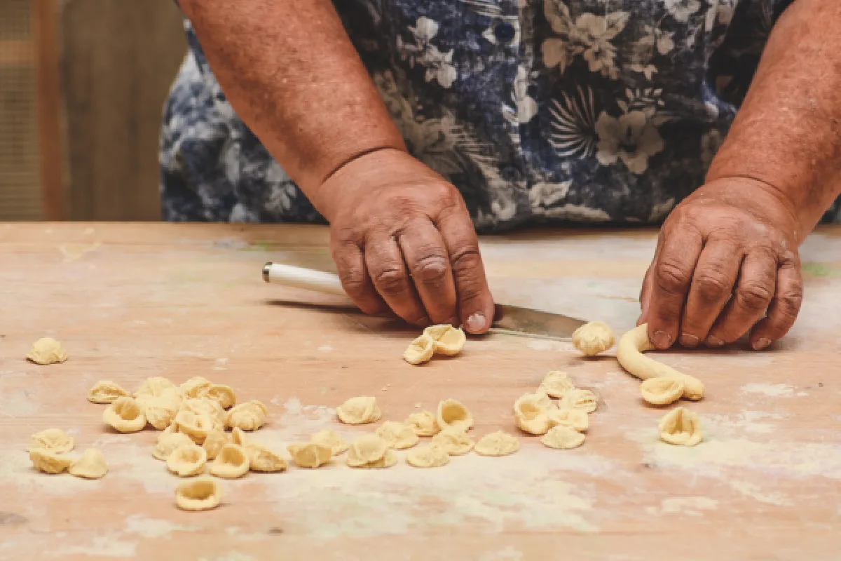 Las manos de una mujer se encuentran haciendo pasta fresca en Italia