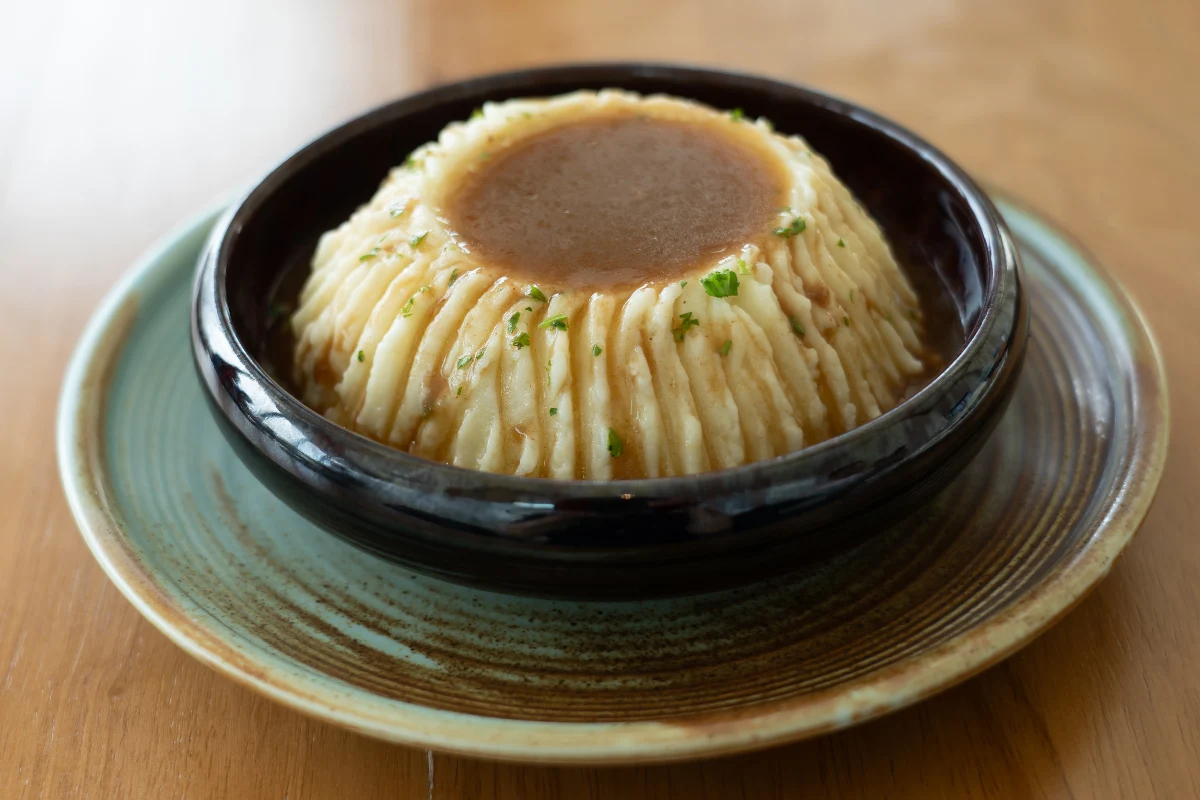 En un tazón hondo se encuentra servido puré de papa con abundante gravy.