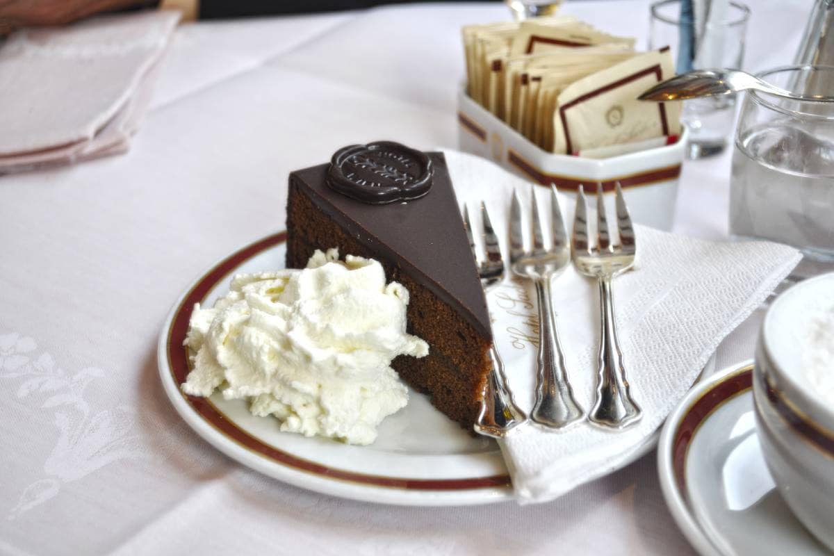 Tarta sacher en restaurante acompañada de crema de nata así como de una bebida caliente 