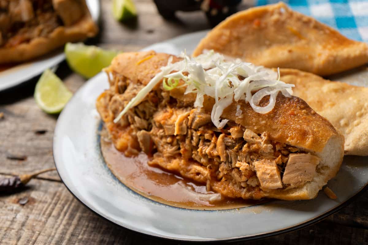 torta ahogada servida en un plato con cebollas y col, gastronomía de Guadalajara