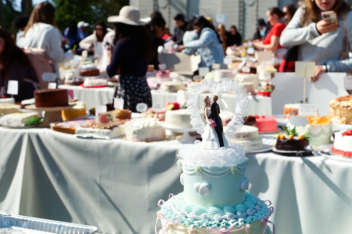 En primer plano se ve un pastel de bodas con unos muñecos que simulan a la pareja de novios y al fondo se ven más pasteles