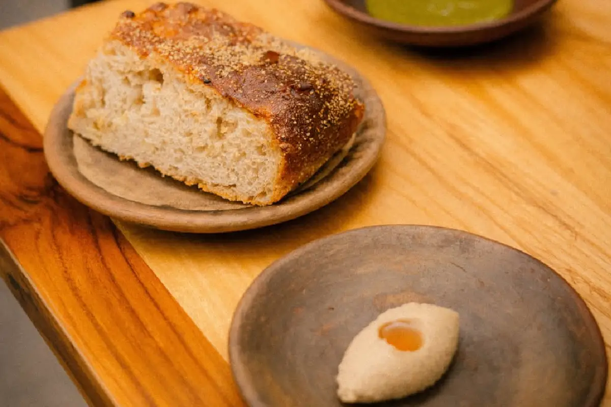 mesa con focaccia de maíz, aceite y dip de cebollas de Baldío