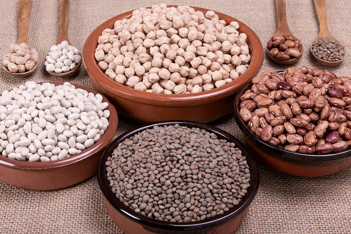 En plato hondos y cucharas se encuentran servidas diferentes tipos de legumbres como lentejas, frijoles, garbanzo.