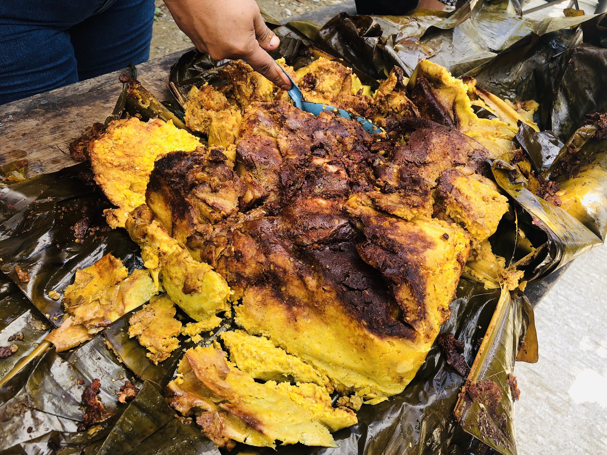 Sobre una hoja de aguacate se encuentra un tamal con salsa llamado patlache