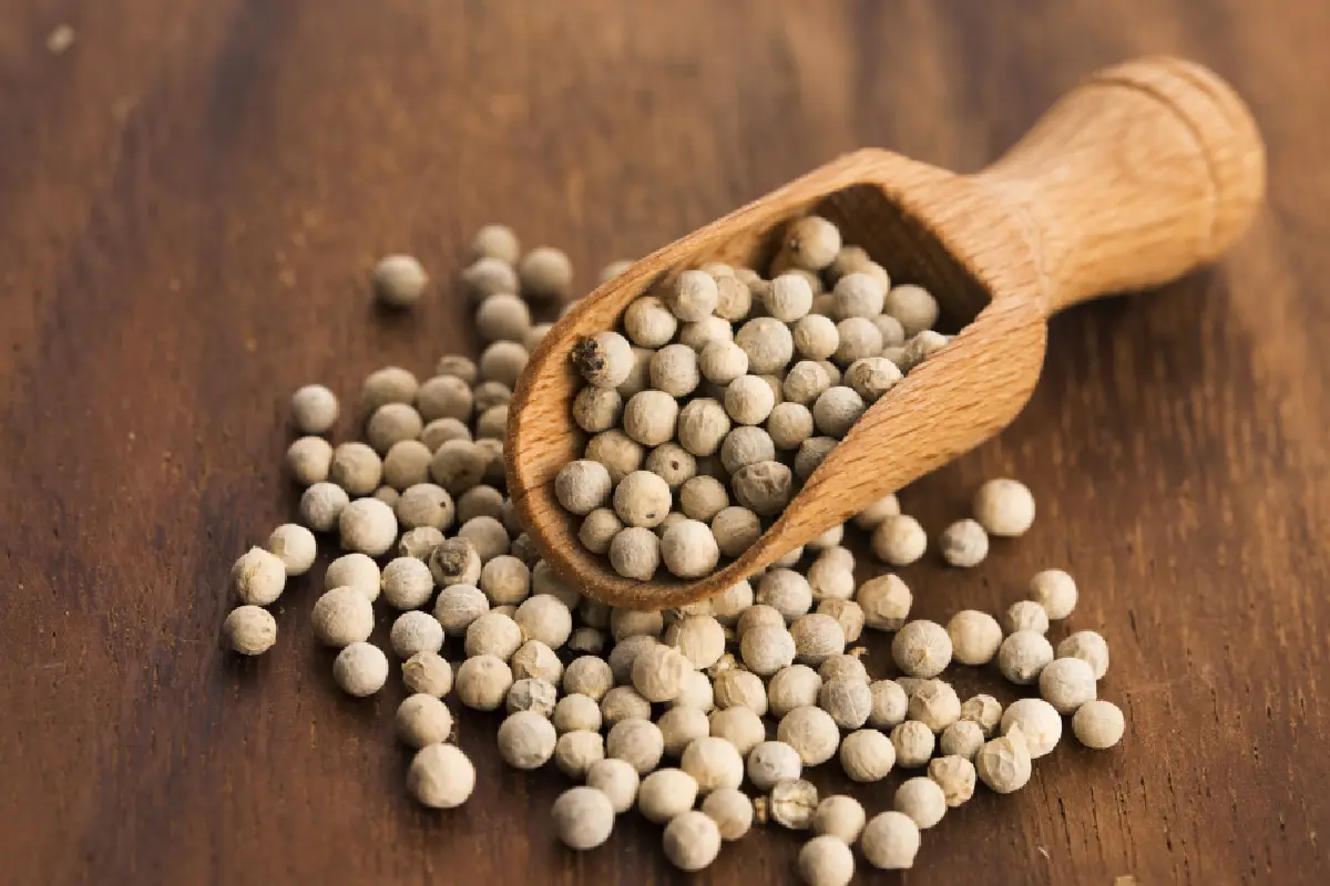 Una pala de madera sostiene una buena cantidad de pimientas blancas.
