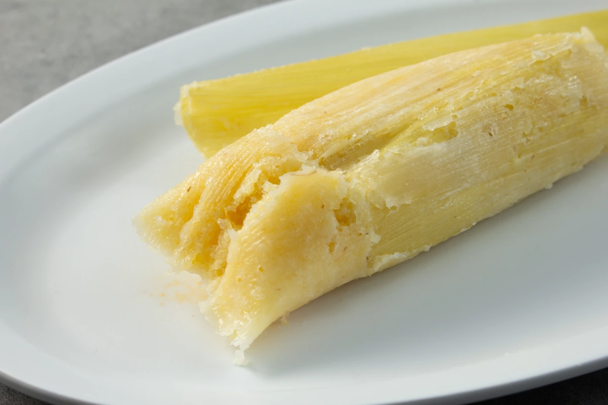 Un tamal de elote sobre un plato blanco.