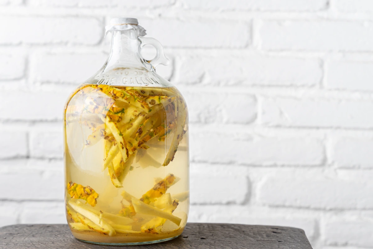 Dentro de un frasco de vidrio se encuentras cáscaras de piña para prepara tepache.