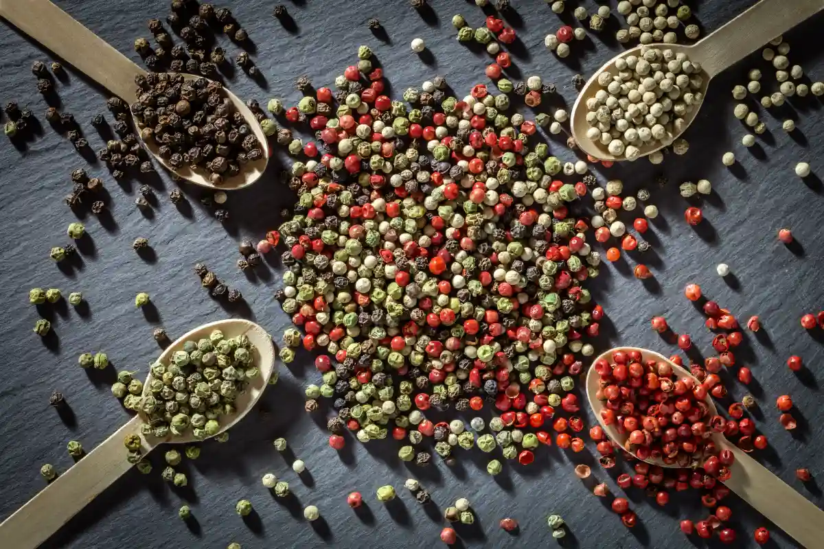 Hay cuatro cucharas a los costados y cada una tiene diferentes tipos de pimienta, al centro hay una mezcla de todas las pimientas.