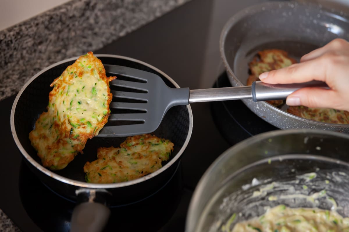 Personas friendo tortitas de aún en aceite.