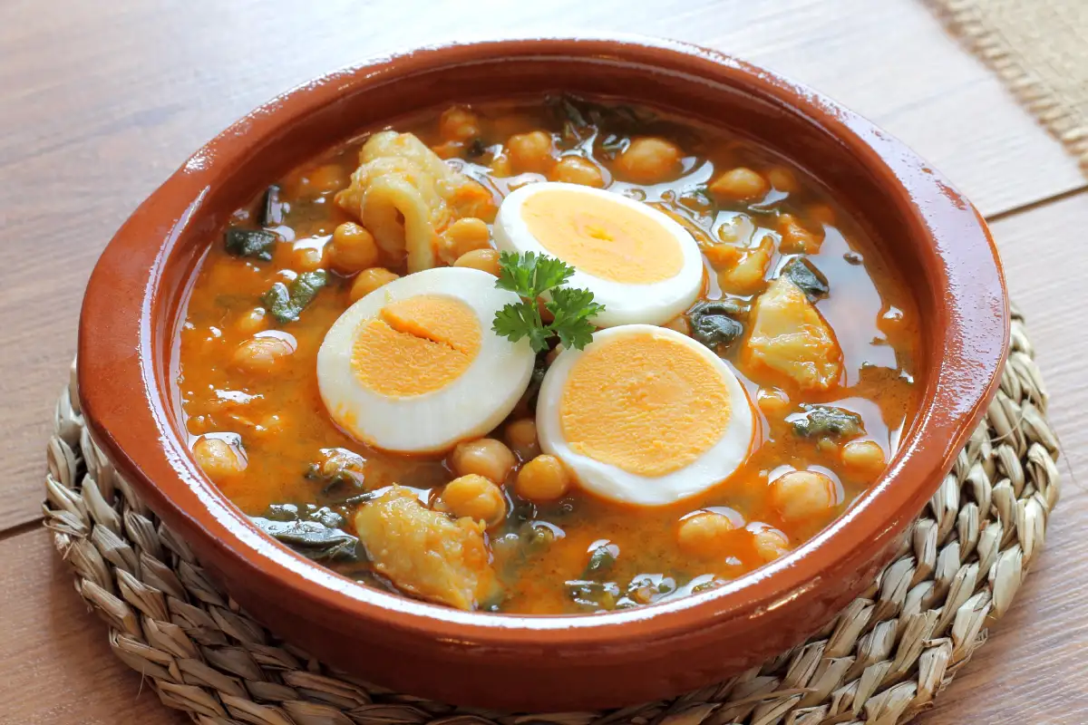 Potaje de vigilia, un plato español, servido sobre un plato de barro recargado en una mesa de comedor.