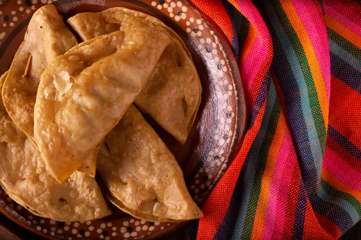 En un plato de barro están servidas quesadillas fritas de sardina.