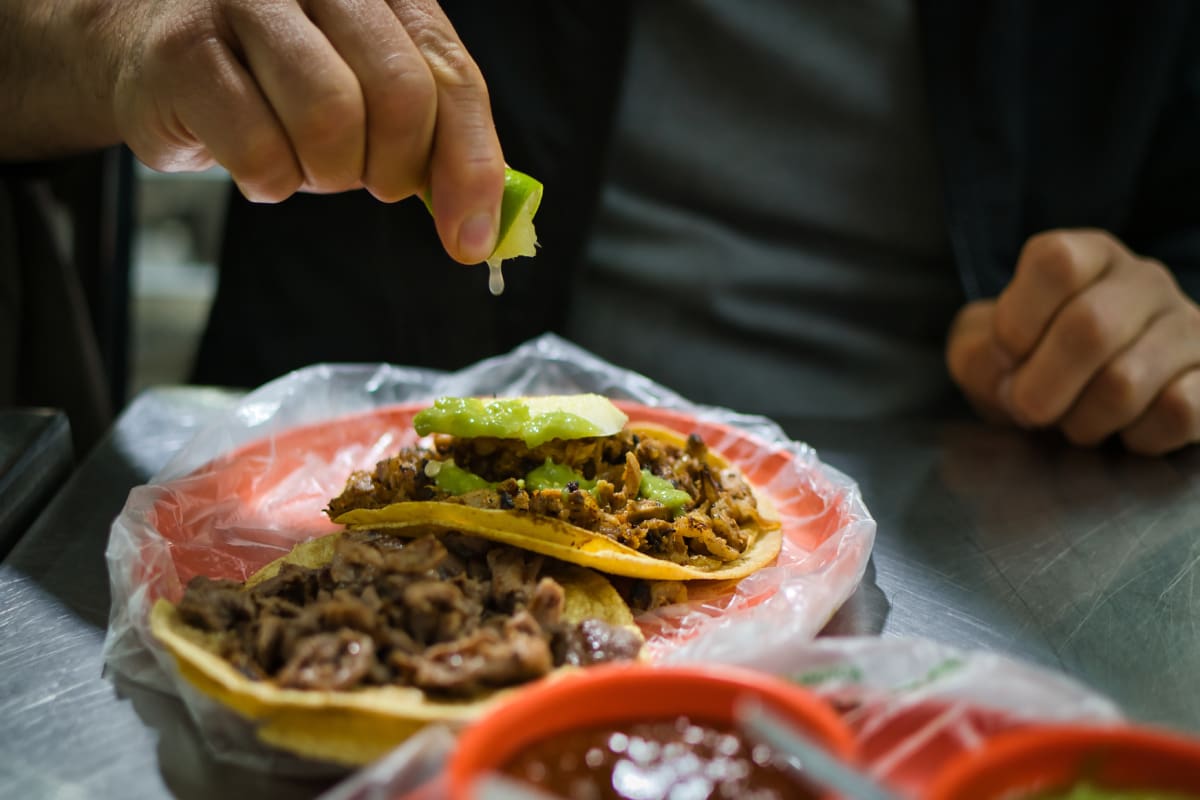Persona poniéndole limón a sus tacos.