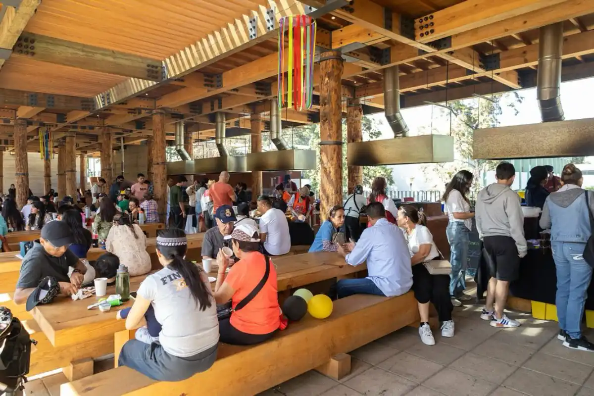 Personas se encuentran comiendo y formadas en las cocinas de humo de Los Pinos